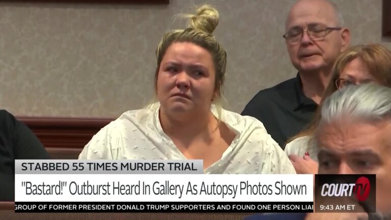 Blonde young woman with hair in a bun and a white blouse cries in court.