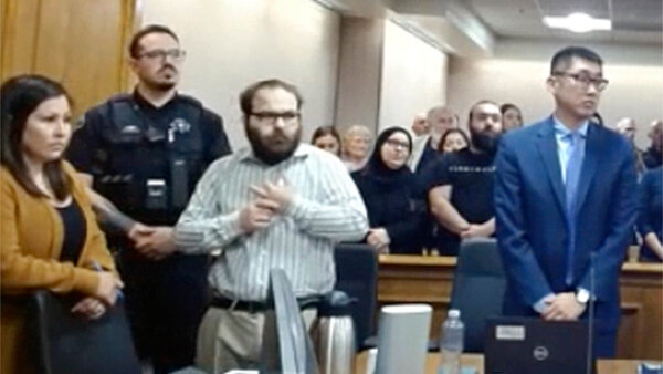 A man stands in court with his attorneys