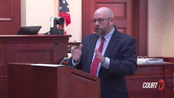 Large, bald, bespectacled attorney speaks animatedly at a podium.