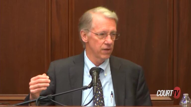 Blonde, middle aged man in a suit testifies.