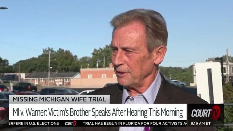 Older gentleman in a suit speaks to a reporter out in the sunshine.