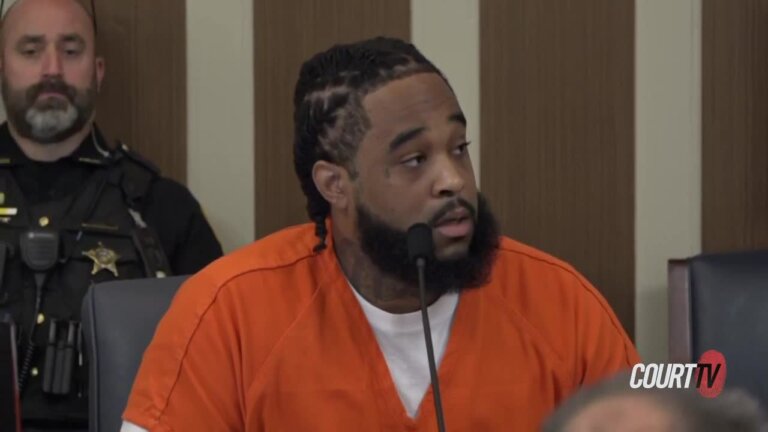 Young bearded defendant speaks into a microphone