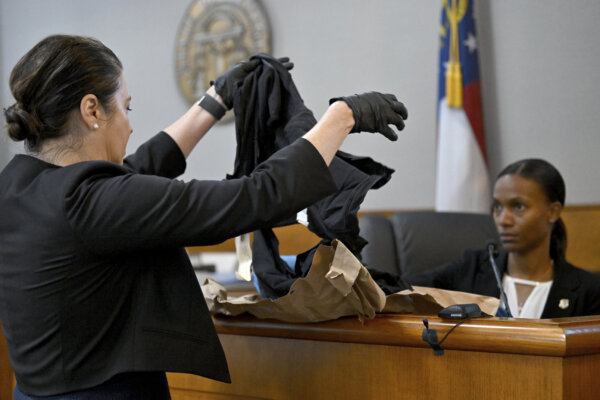 Prosecutor holds up cut, shredded clothing for witness
