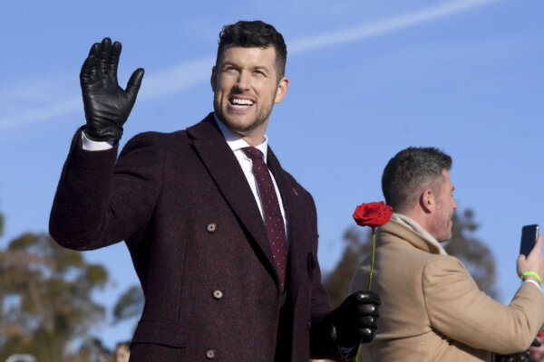 Clayton Echard waves while holding a rose.