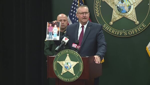 man holds photograph at lectern