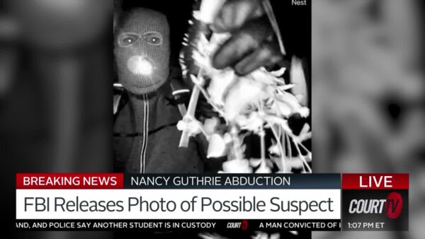 man in mask holds up object in surveillance image