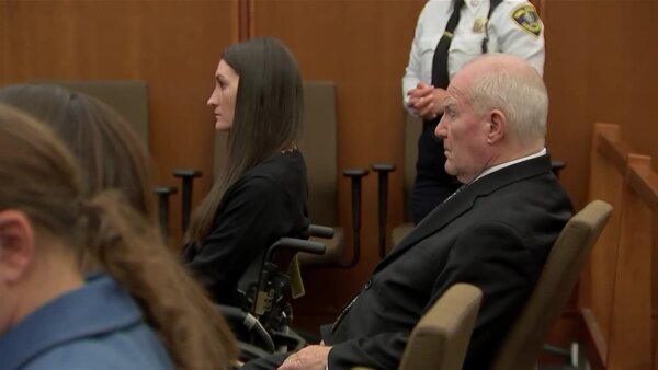 woman in wheelchair sits in court next to attorney