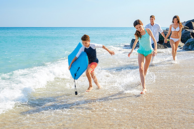 A family of four splash in the water at The Breakers private beach