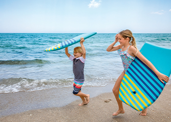 Children walking along the beach with boogie boards at The Breakers Palm Beach