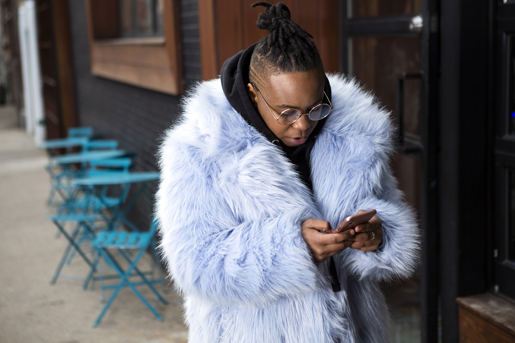 5c99852cbded5d1906be4d79_A-transmasculine-person-with-a-furry-blue-coat-checking-his-phone-on-the-sidewalk.jpg