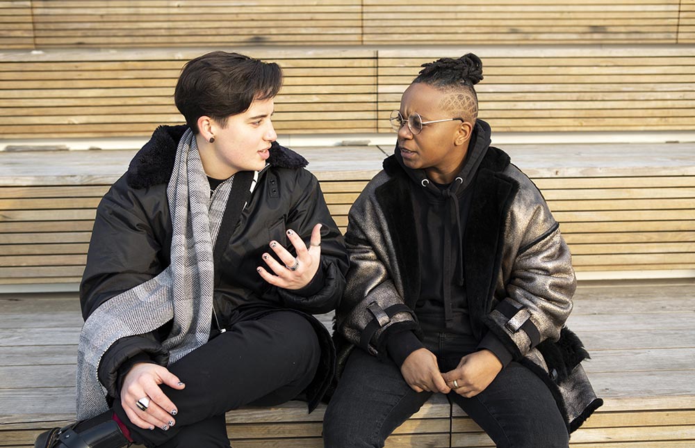 5c998a7e5b8ede1252420cce_Two-transmasculine-people-sitting-together-and-having-a-serious-conversation.jpg