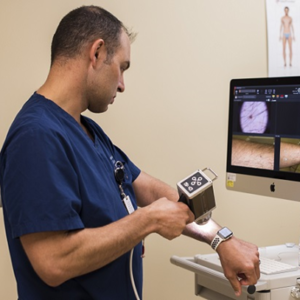 Air Force Maj. Thomas Beachkofsky, 6th Health Care Operations Squadron dermatologist, uses a body scanner microscope to take a picture of a spot on his arm at MacDill Air Force Base, Florida. A new software upgrade allows a complex algorithm to analyze an image captured with a camera and rate the severity of the spot for a dermatologist to review. (U.S. Air Force photo by Senior Airman Adam R. Shanks)