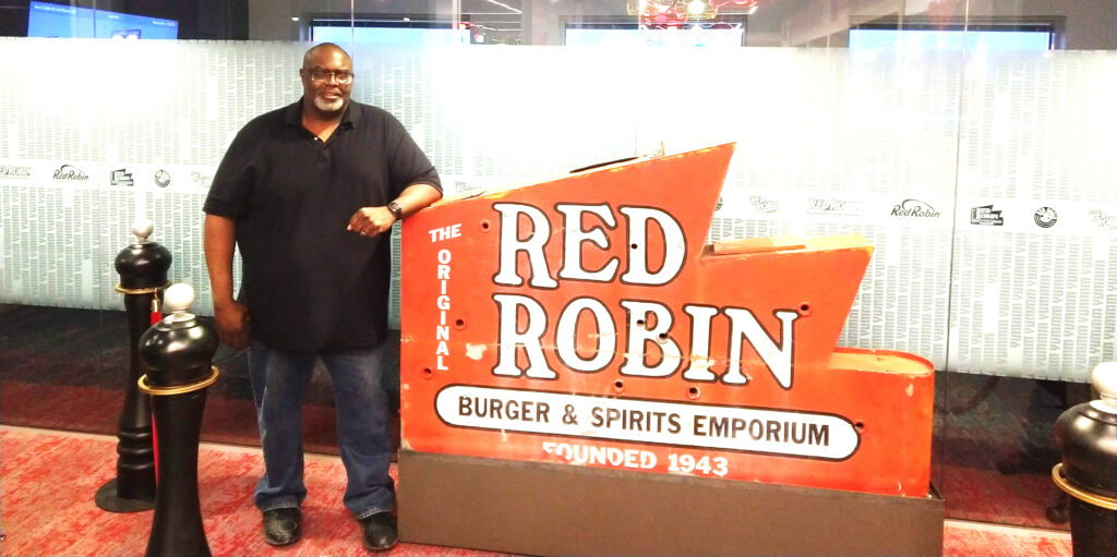 Preston Thornton with the sign for Red Robin, where he helped implement a serverless ordering system.