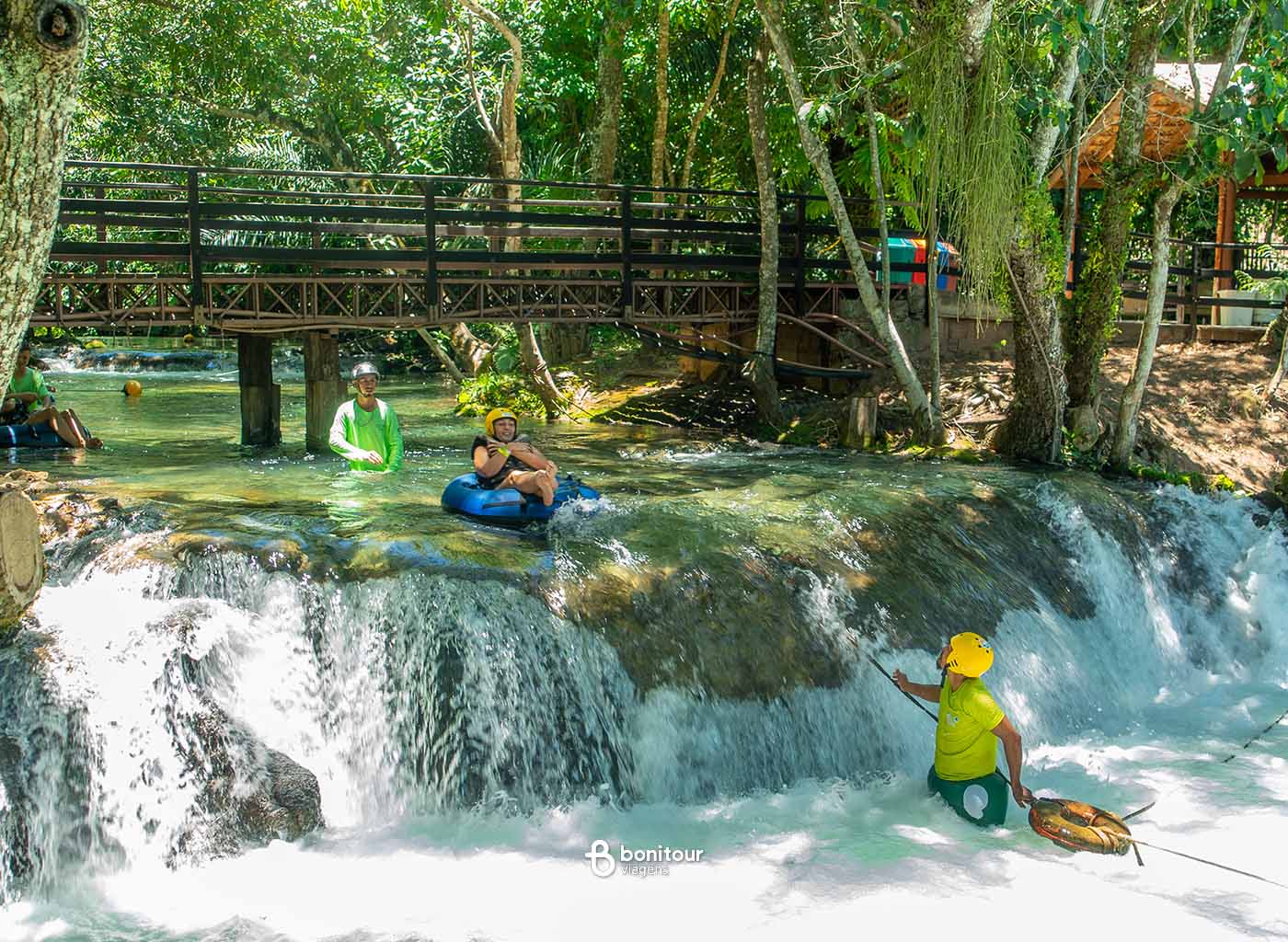 Pessoas descendo de boia em queda d'água com ajuda de instrutor