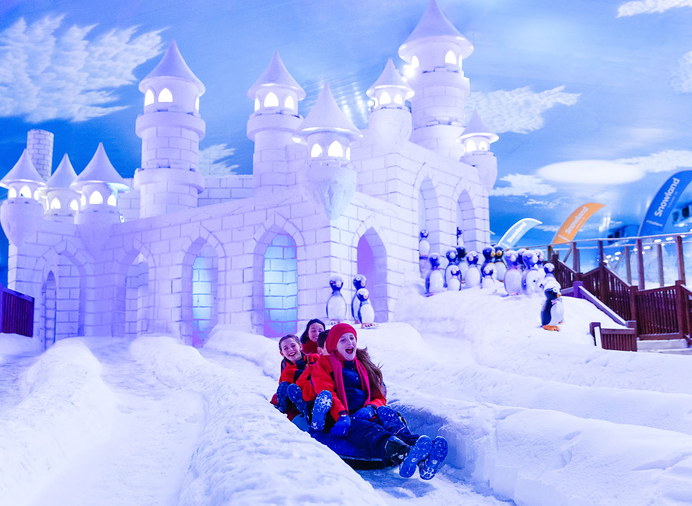 Crianças brincando de escorregar no gelo com castelo de Snowland de fundo