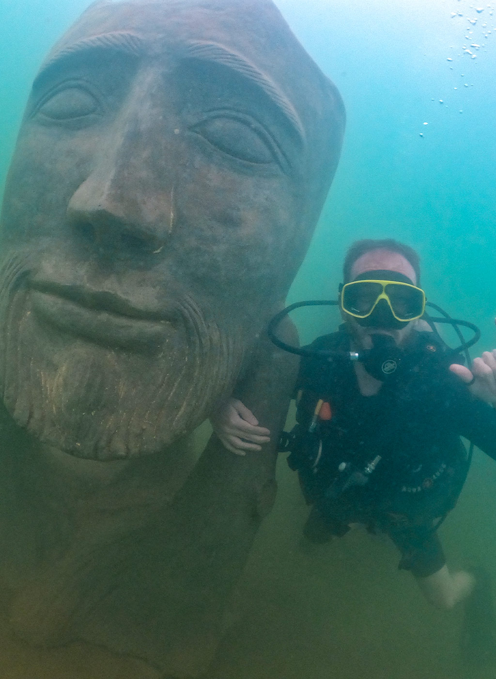 Mergulhador se divertindo em baixo da água com estátua do Museu Subaquático