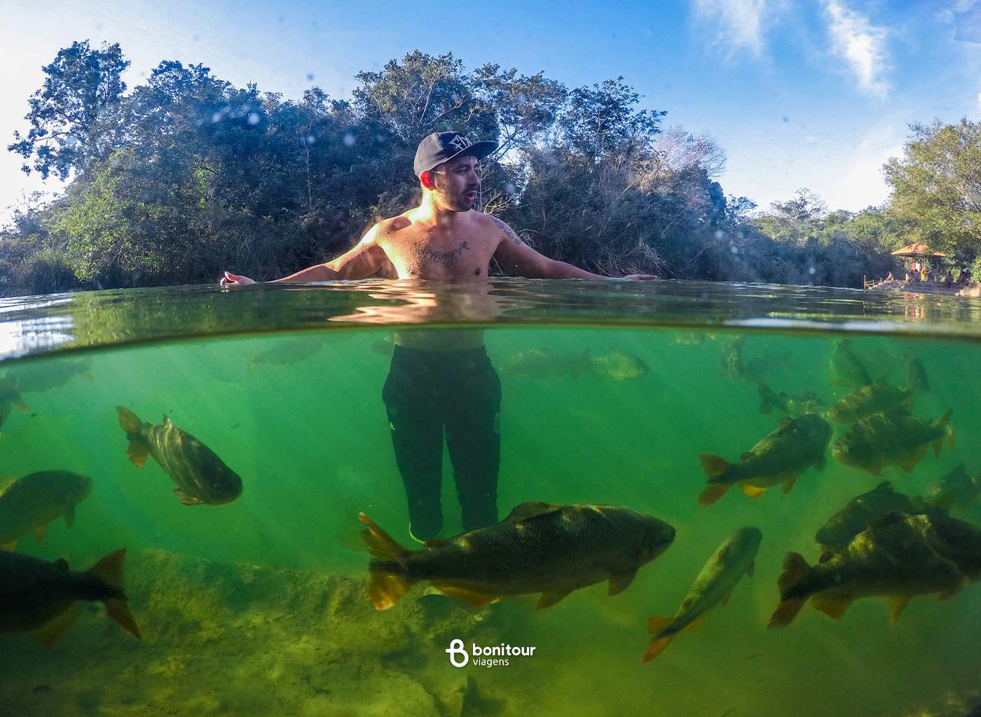 Homem dentro do Rio Formoso com cardumes de peixes ao redor