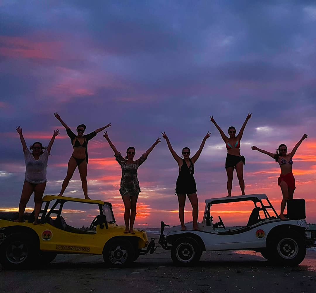 Grupo comemorando sobre buggies ao entardecer em Jericoacoara