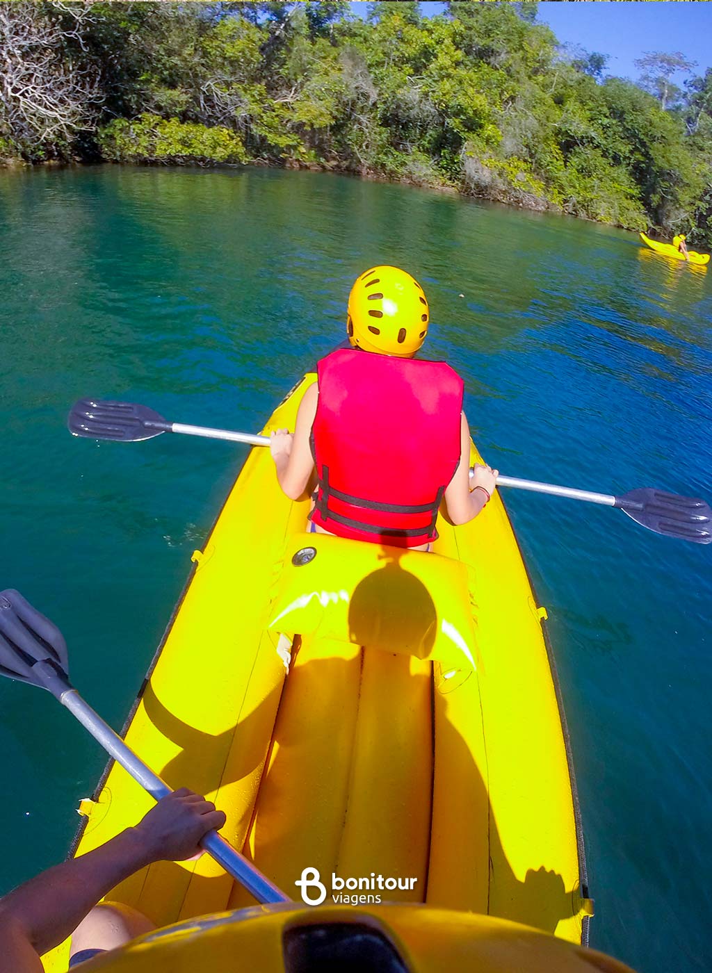 Pessoa dentro de bote a remo, com equipamento de proteção navegando pelo rio