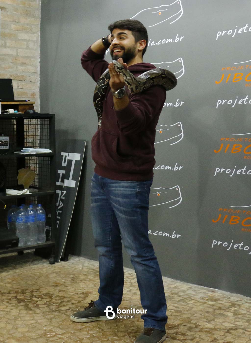 Pessoa segurando serpente jiboia nos ombros