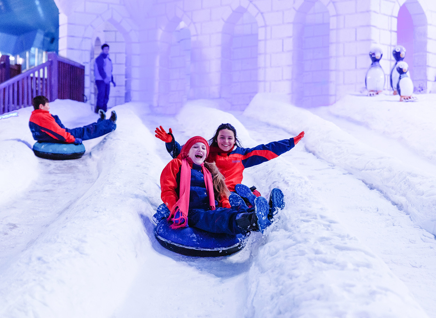 Crianças brincando de escorregar no gelo com castelo de Snowland de fundo