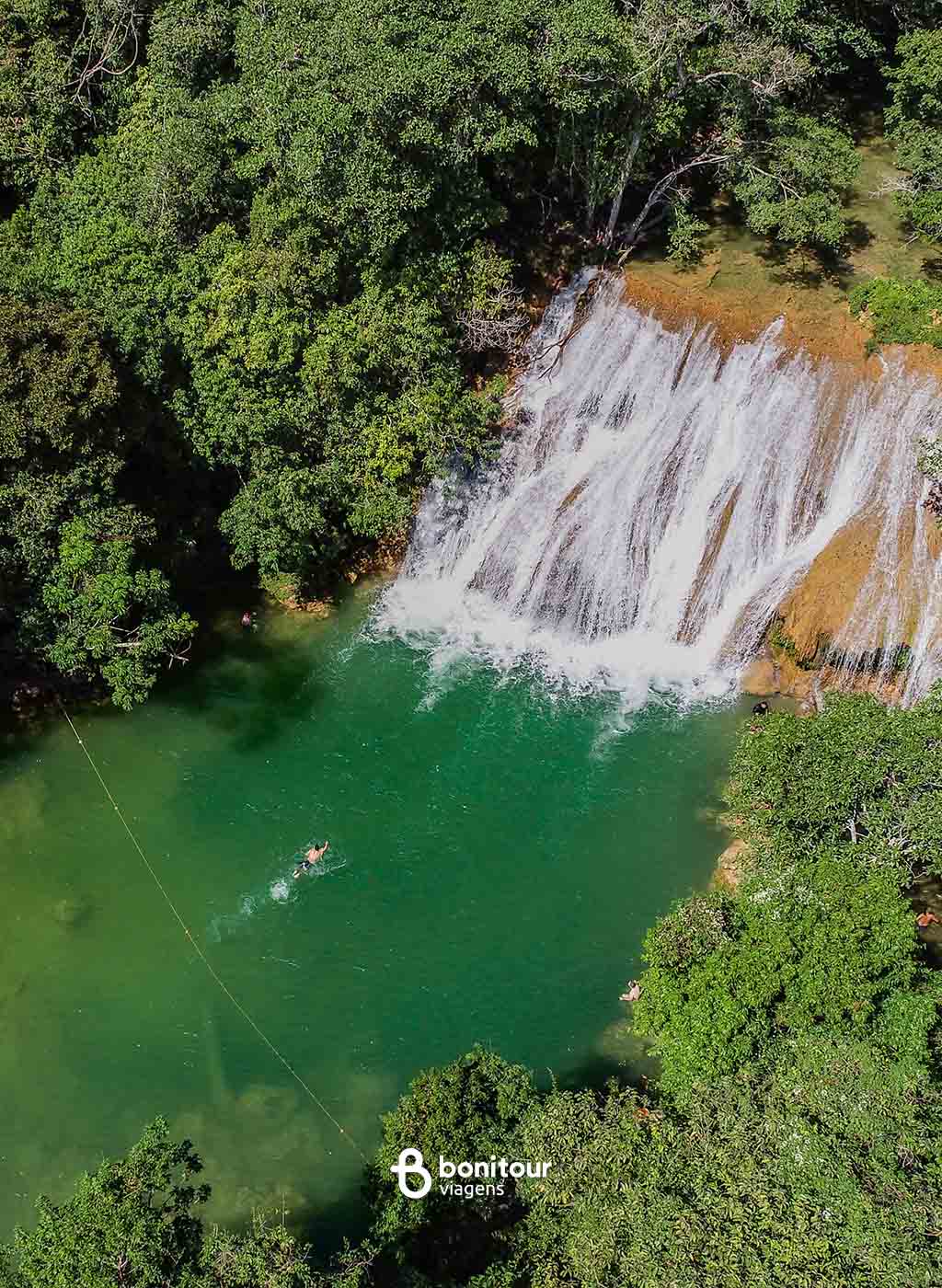 Pessoa nadando em direção às quedas d'água da Cachoeira Serra da Bodoquena