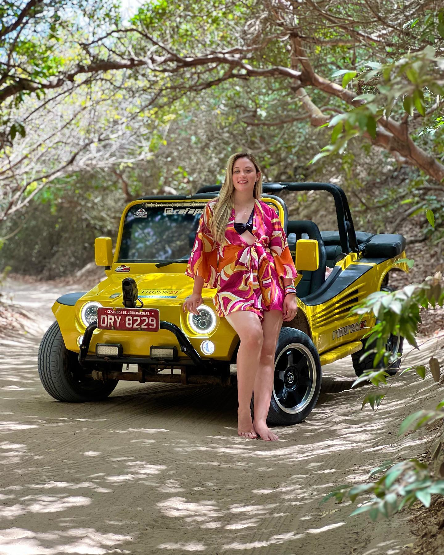 Turista posando com buggy amarelo em trilha do Lado Leste de Jericoacoara