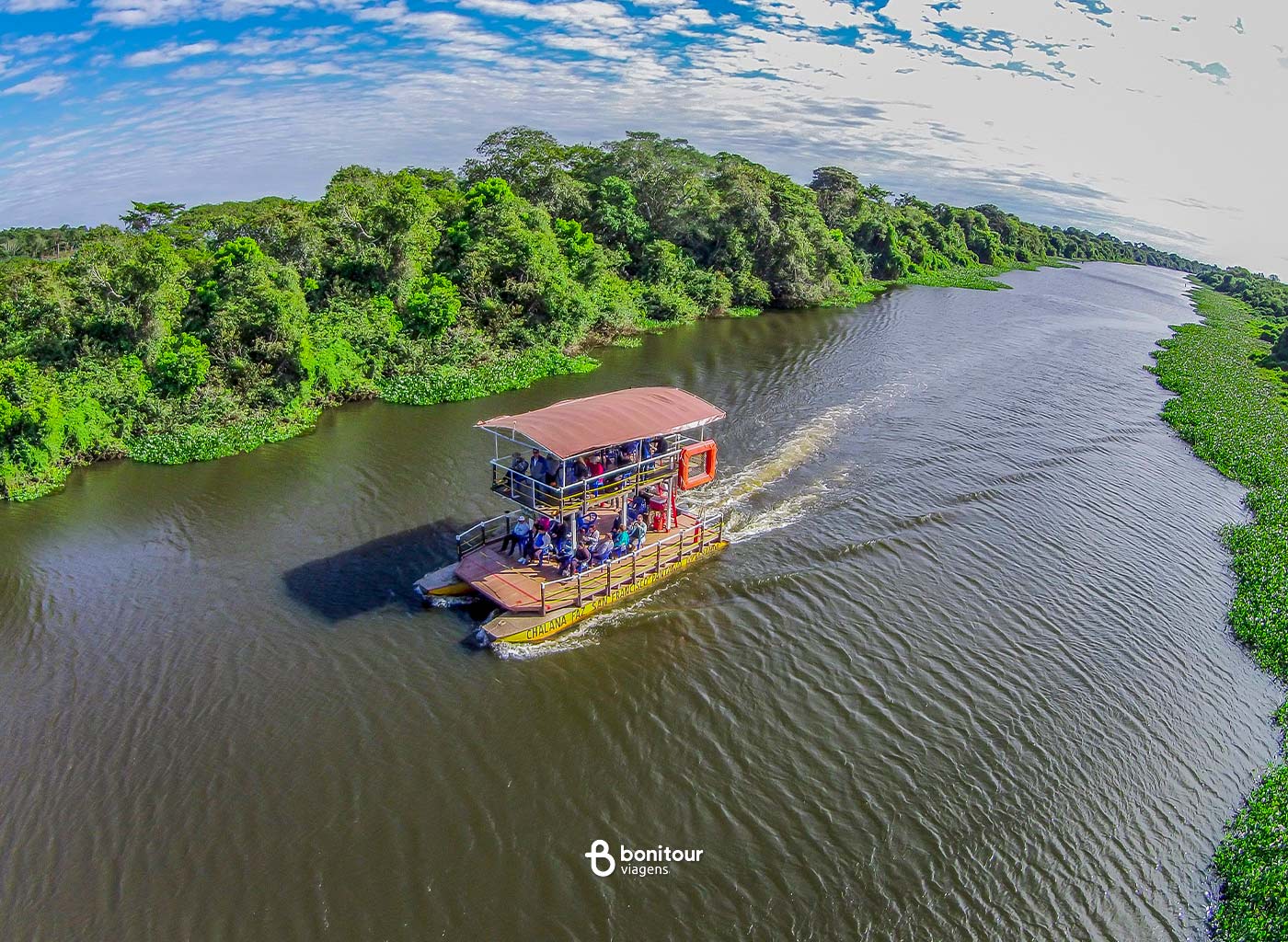Barco de dois andares navegando pelas águas do Pantanal