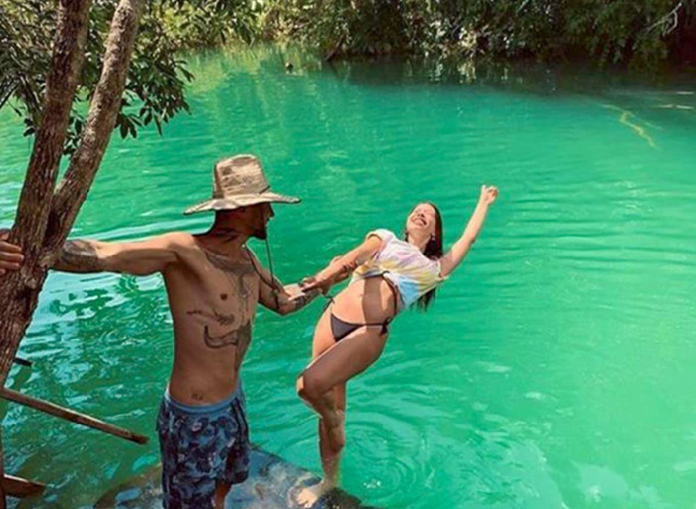 Casal brincando à margem de águas cristalinas em meio a natureza