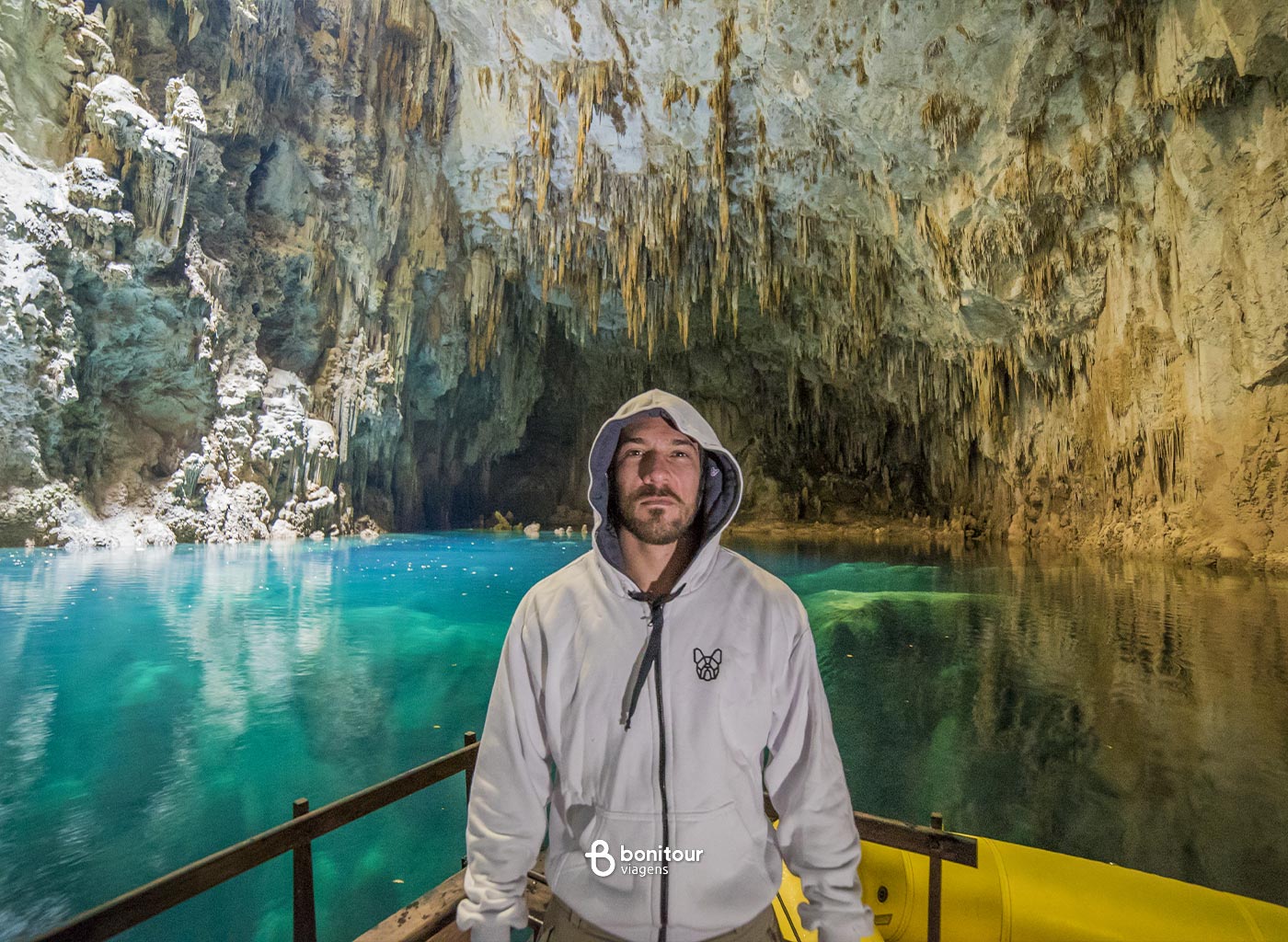 Pessoa em deck dentro do Abismo Anhumas com águas cristalinas e formações rochosas