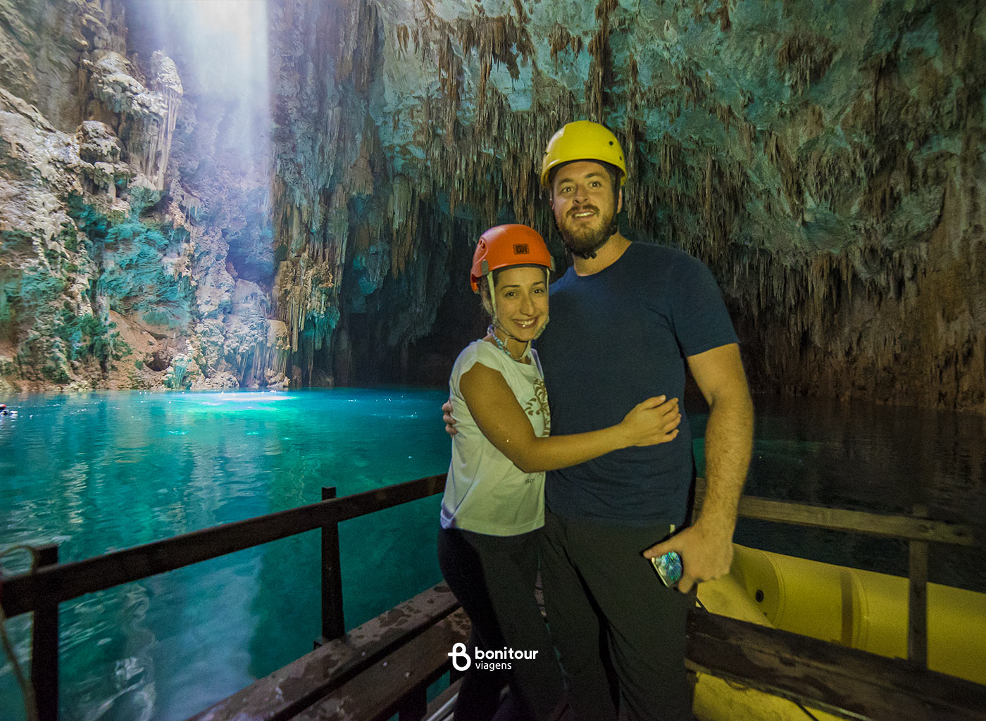 Casal parado em deck de madeira dentro do Abismo anhumas