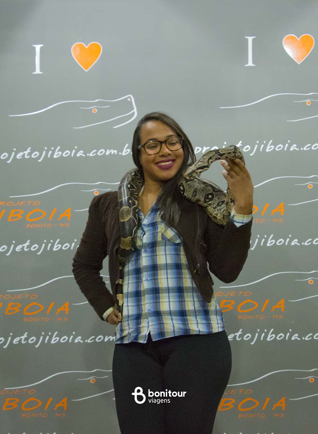 Mulher segurando serpente jiboia nos ombros