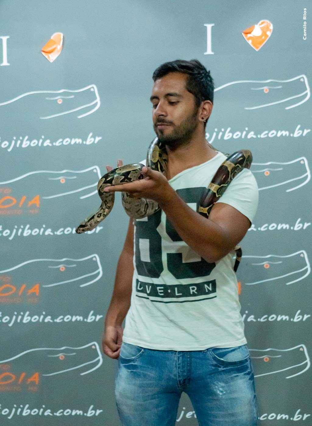 Homem segurando serpente jiboia nos ombros