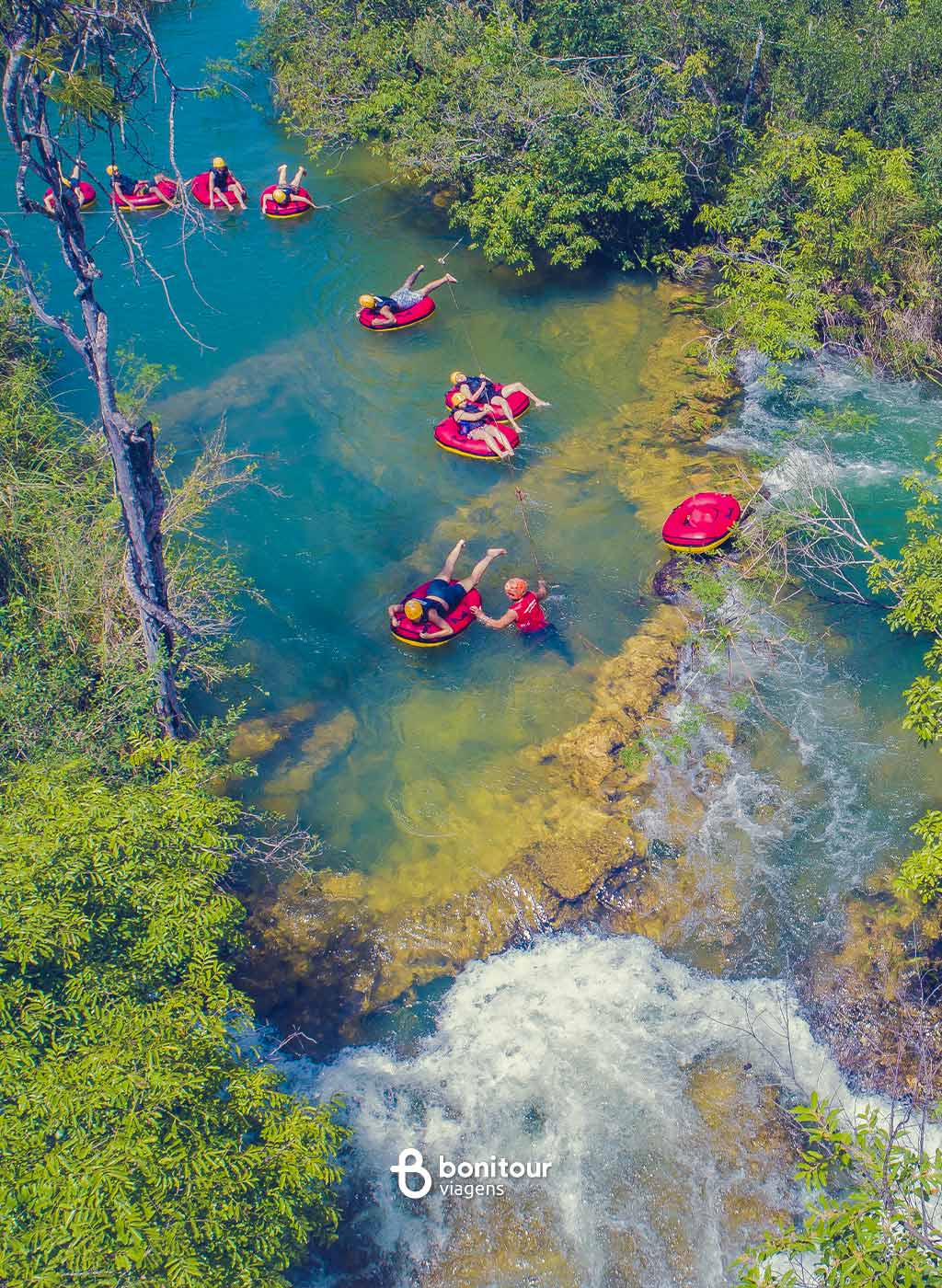 Pessoas de boia descendo pelas águas do rio Formoso em meio a natureza