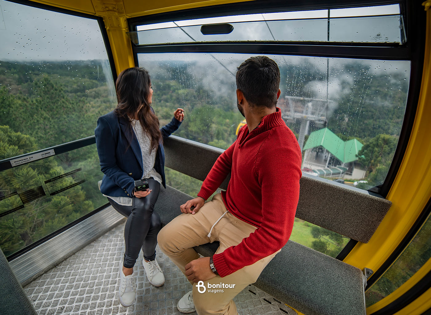 Duas pessoas dentro de Bondinho observando a natureza que fica a baixo