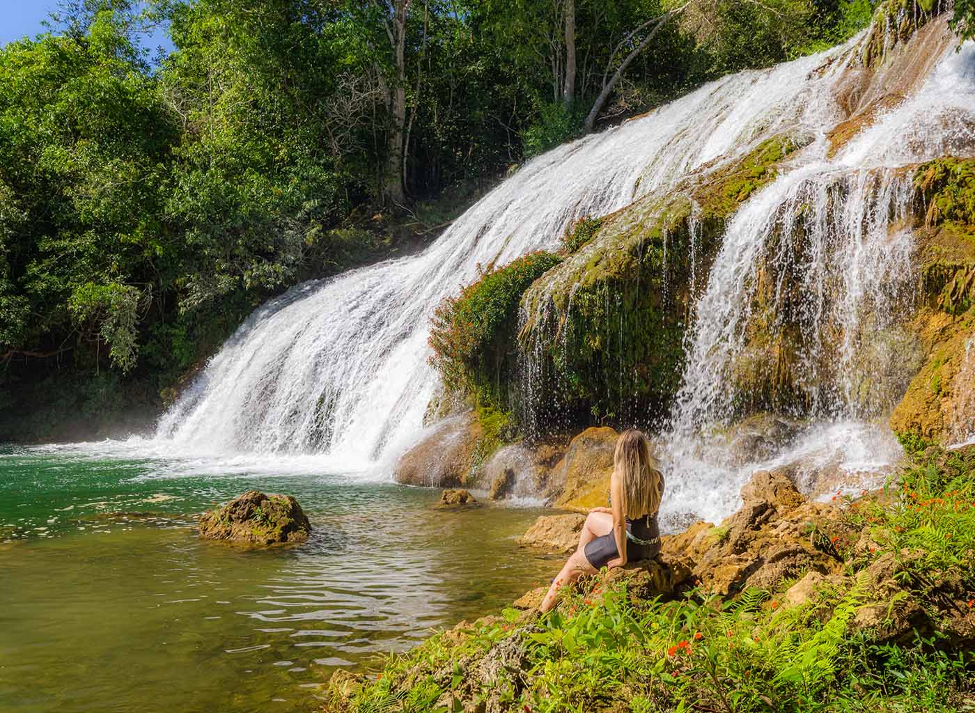 Mulher sentada na pedra observando a cachoeira da gruta nas cachoeiras da Serra da Bodoquena