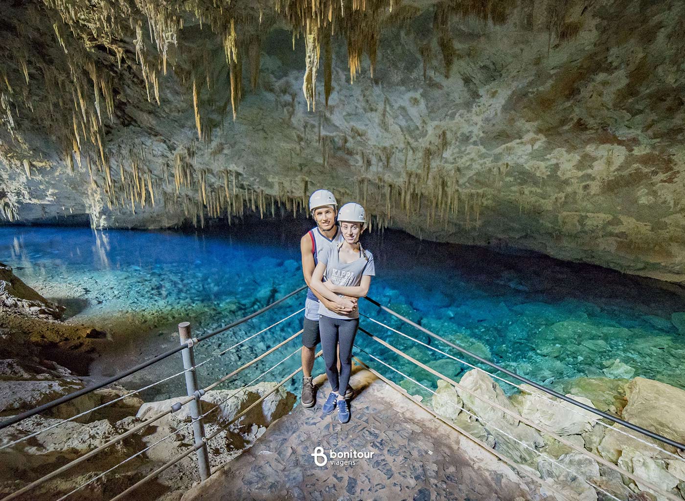 Pessoas contemplando vista da Gruta do lago azul com águas cristalinas azuis e formações rochosas