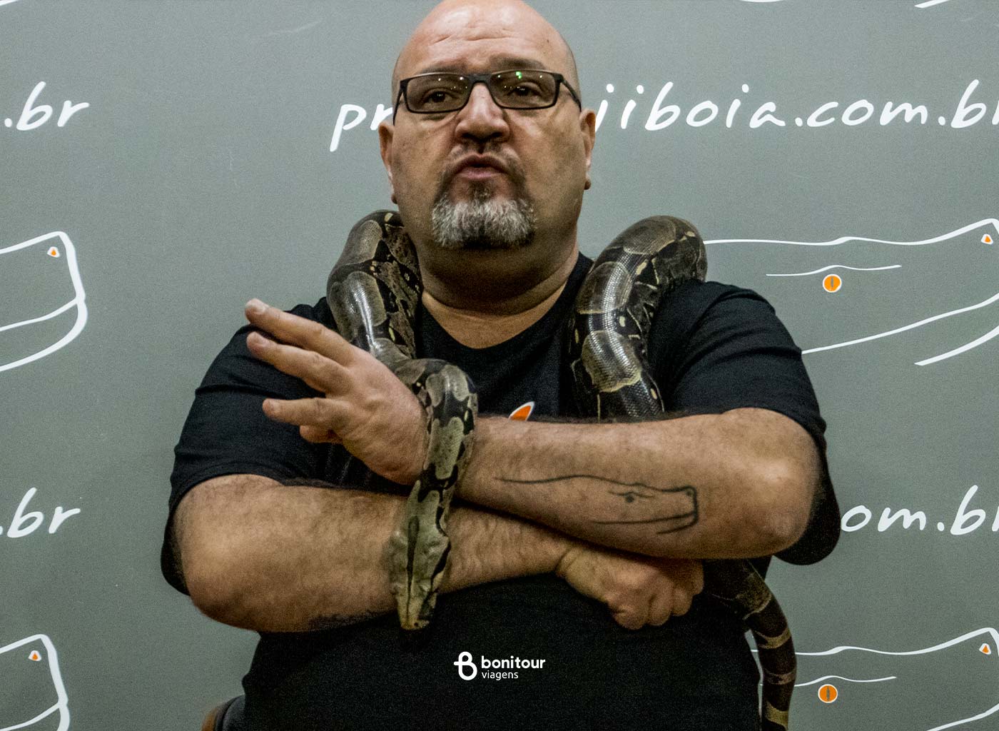 Homem segurando serpente jiboia nos ombros