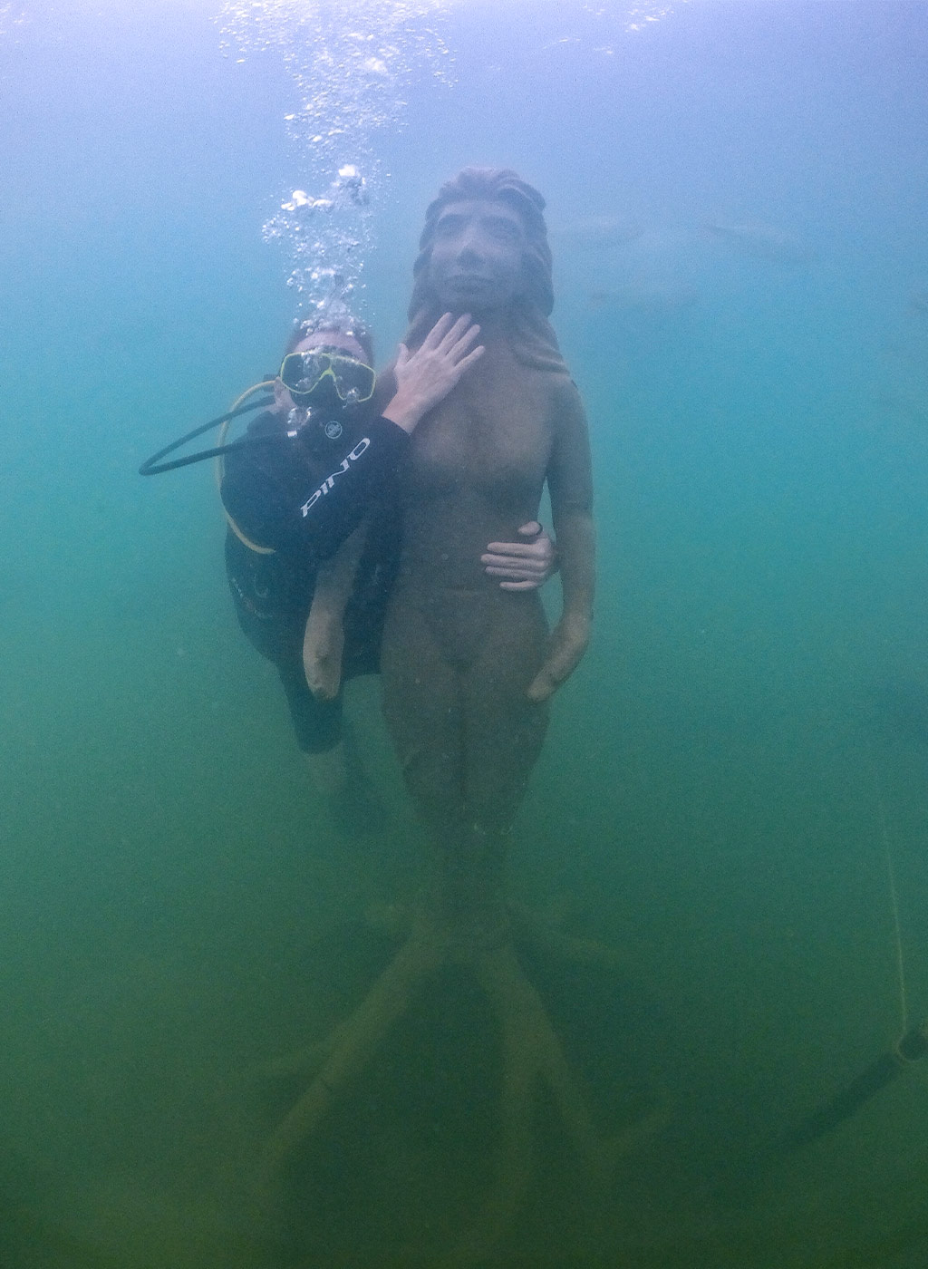 Mergulhador se divertindo em baixo da água com estátua do Museu Subaquático