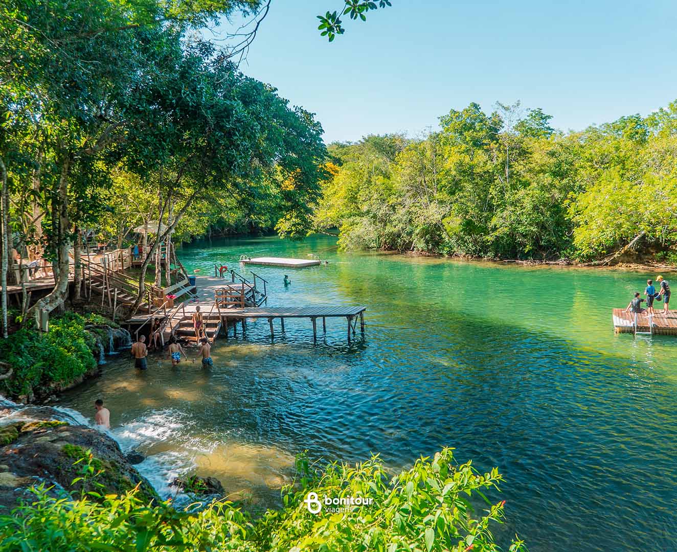 Deck de madeira a beira de águas cristalinas e cachoeira