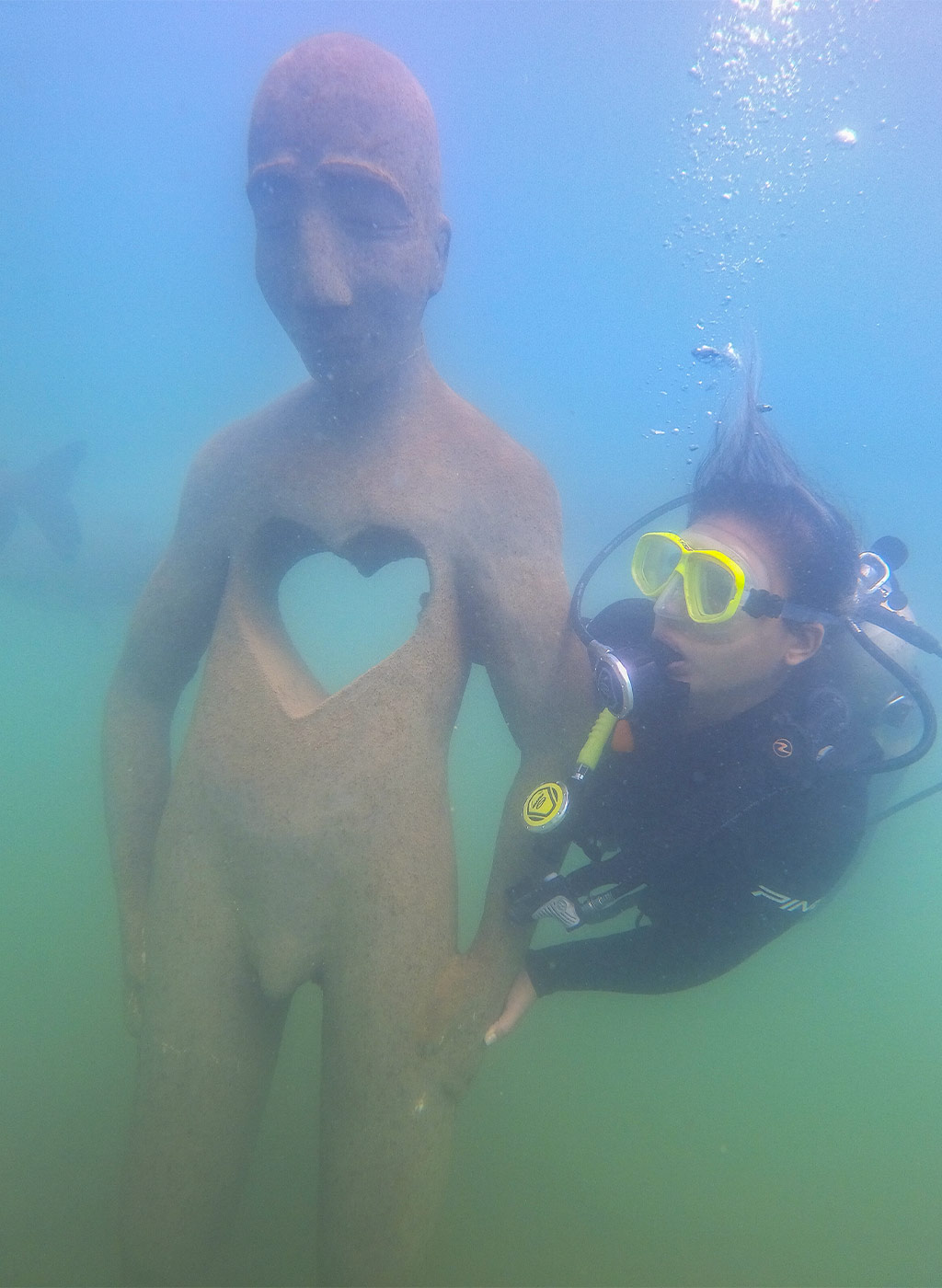 Mergulhador se divertindo em baixo da água com estátua do Museu Subaquático