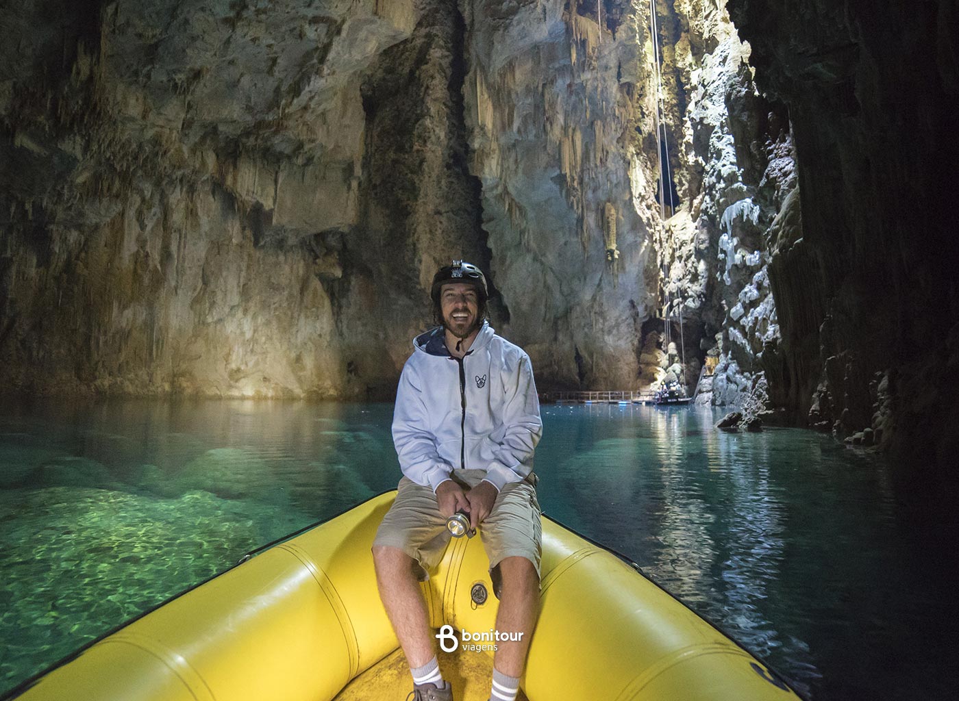Pessoa de bote dentro do Abismo Anhumas com águas cristalinas e formações rochosas