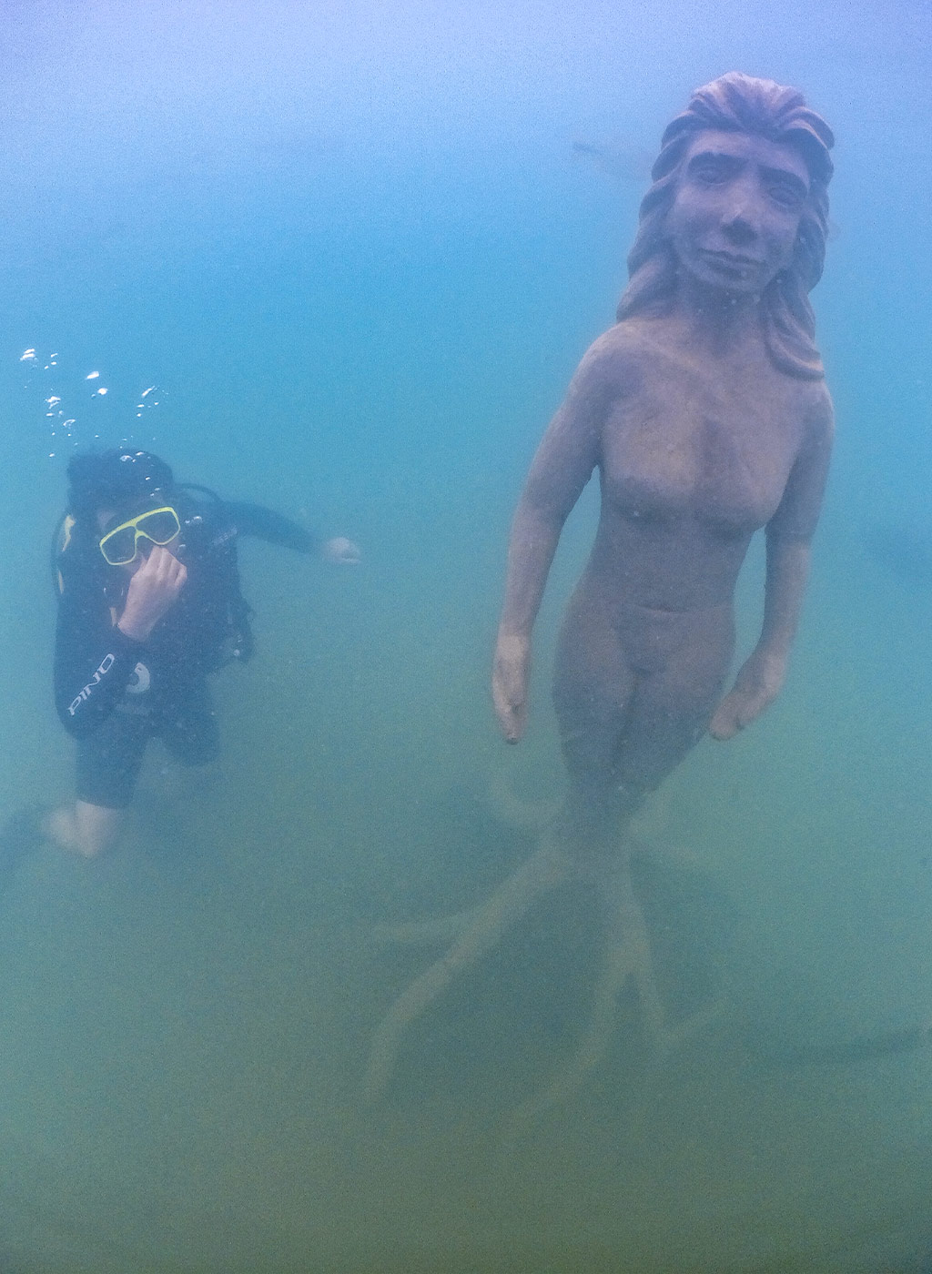 Mergulhador se divertindo em baixo da água com estátua do Museu Subaquático