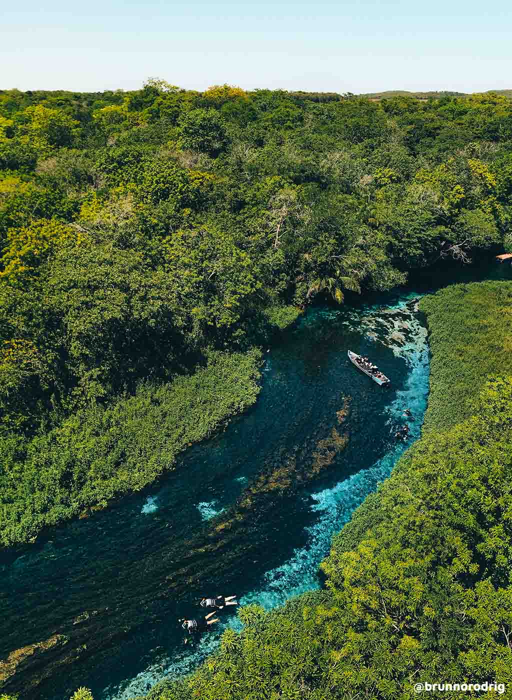 Vista do alto do Rio Sucuri, com barco navegando e densa vegetação.