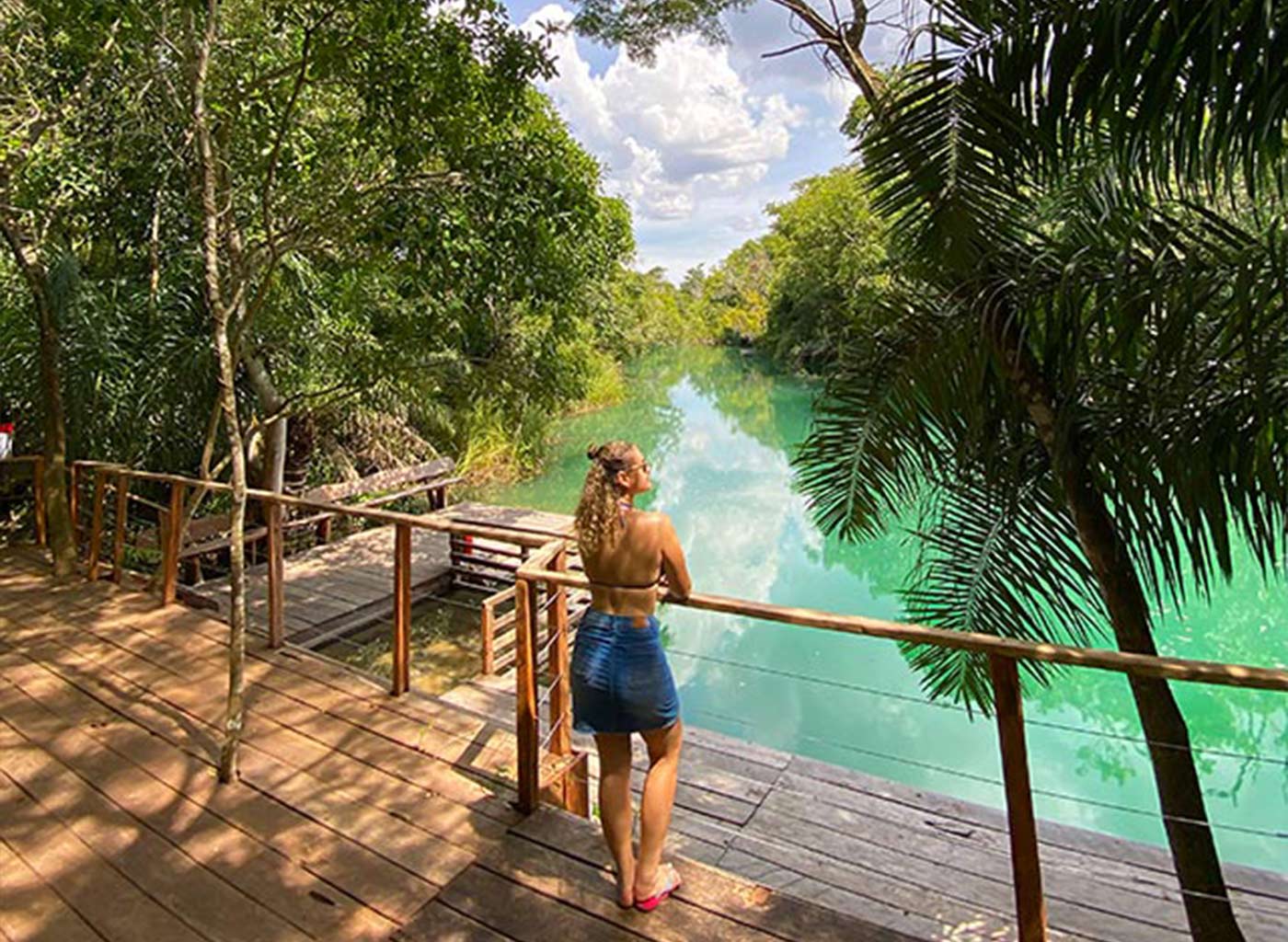 Mulher parada em deck de madeira observando a natureza