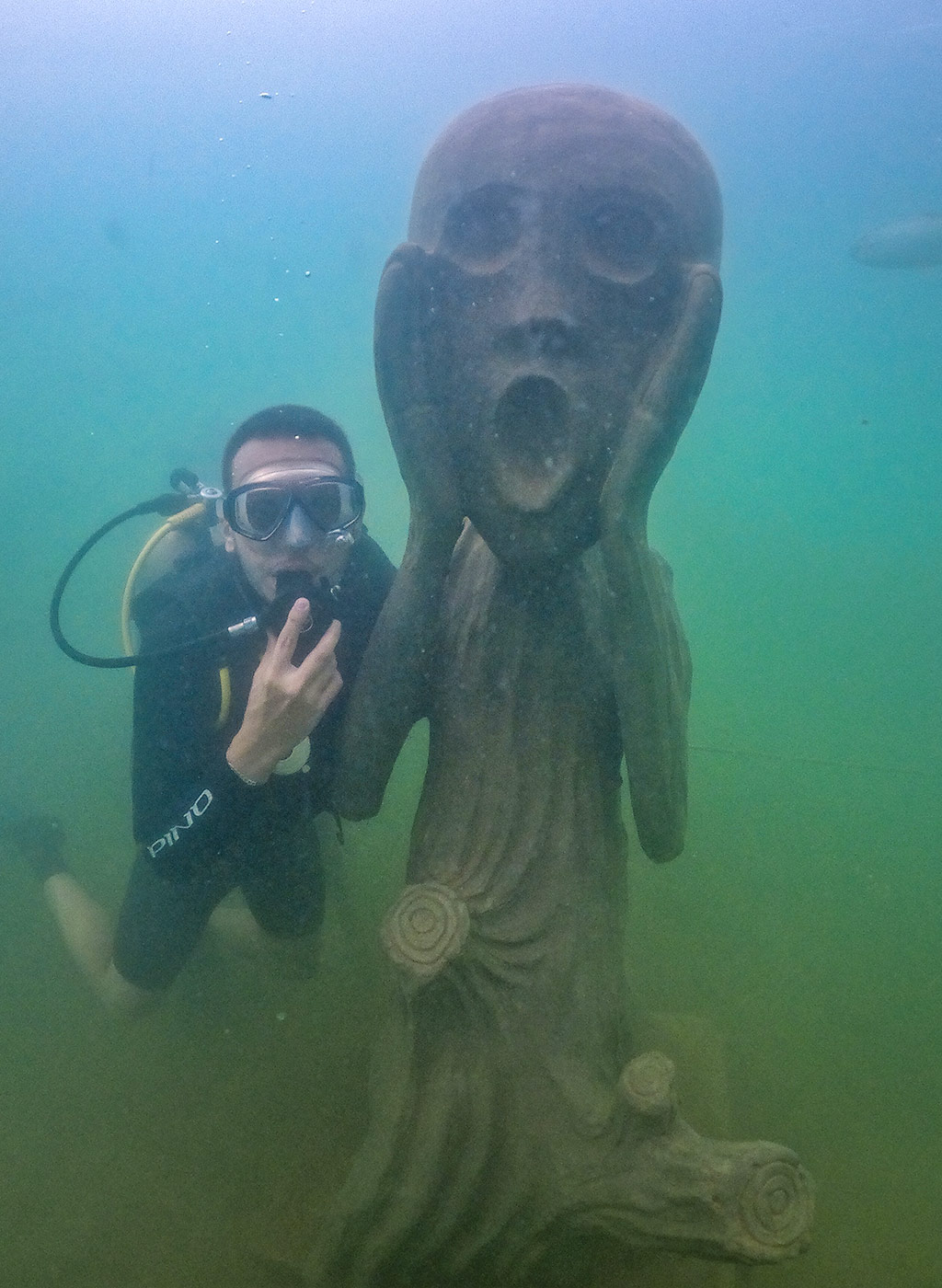 Mergulhador se divertindo em baixo da água com estátua do Museu Subaquático