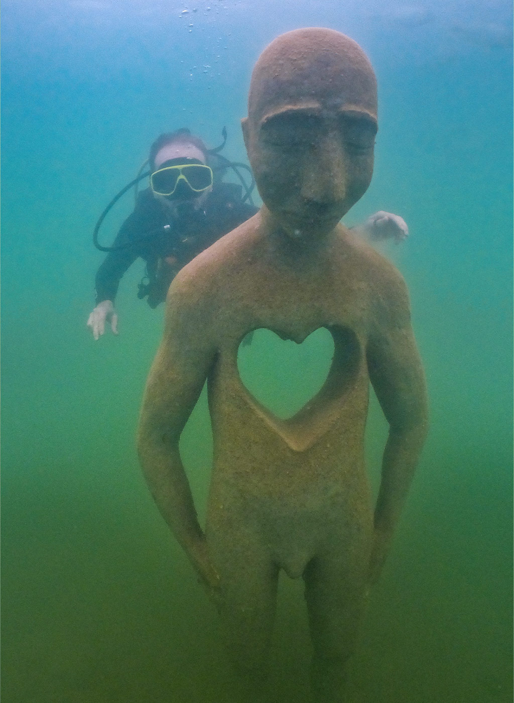 Mergulhador se divertindo em baixo da água com estátua do Museu Subaquático