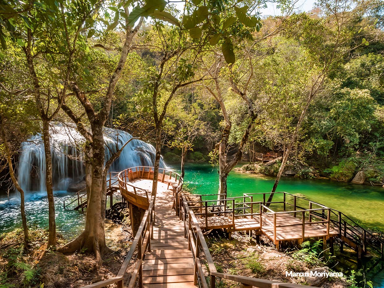 Vista de um deck no Parque das Cachoeias com quedas d'água ao fundo e vegetação exuberante.