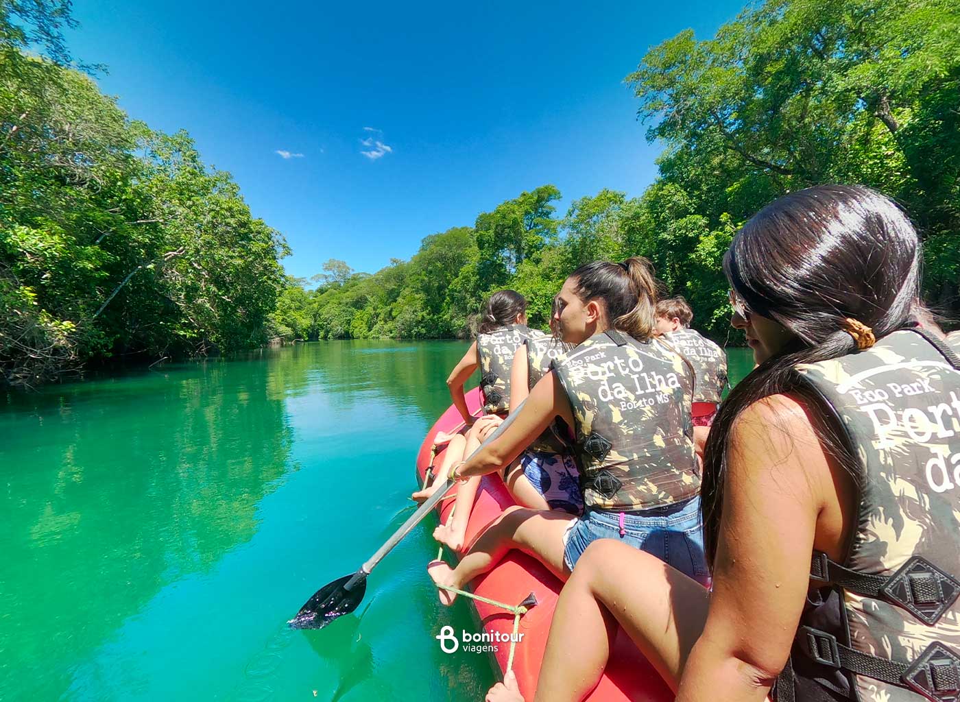 Pessoas navegando em bote inflável a remo em meio as águas de Bonito