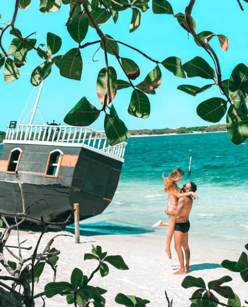 Casal posando ao lado de barco na Praia de Barrinha